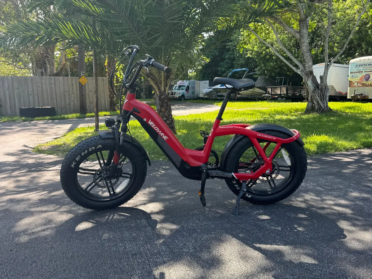 This exterior image centers on a red electric bike set against surrounding greenery and a paved pathway. The scene evokes a sense of adventure and accessibility, suggesting the ease with which guests can explore the local area or commute to nearby attractions.