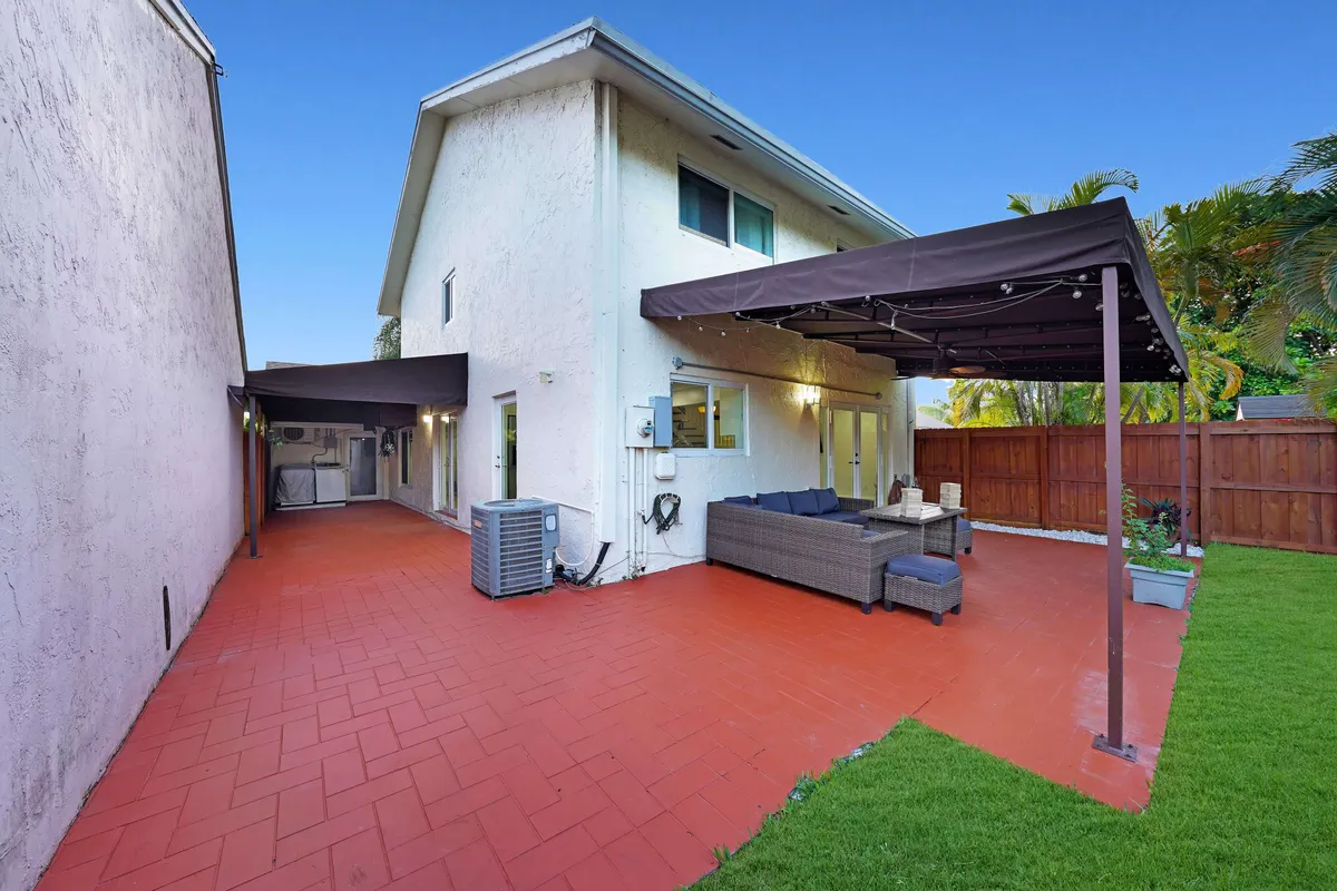 This exterior shot showcases a covered patio area with a canopy, modern seating, and a lush green lawn beyond. It's set up for outdoor dining or movie nights under the stars, with a sense of both comfort and adventure.